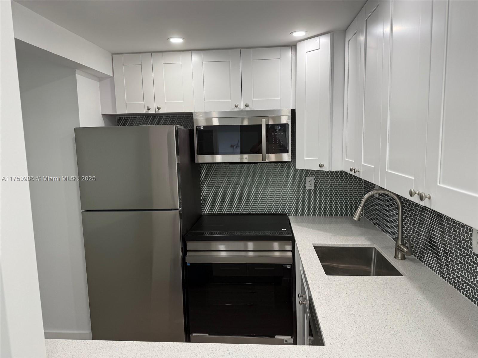 926 Michigan Avenue, Unit 12 Miami Beach, FL 33139 - Photo 3 of 14 a kitchen with a refrigerator sink and cabinets