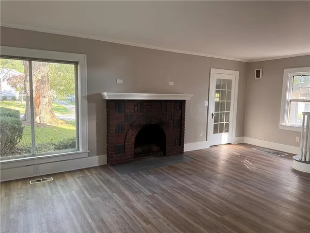 wooden floor fireplace and windows in an empty room