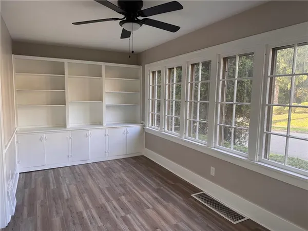 a view of an empty room with a window and wooden floor
