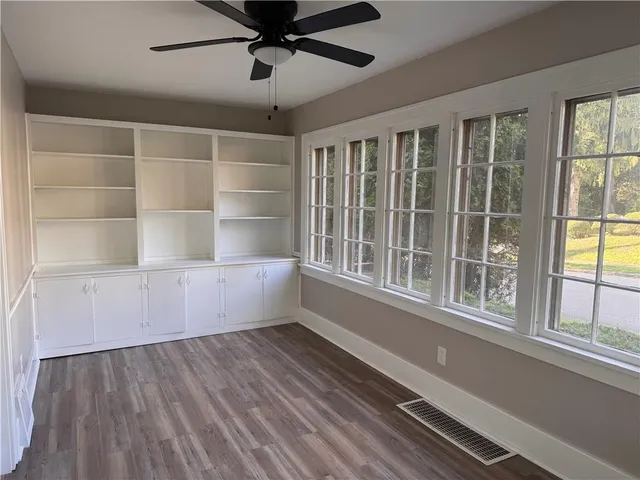 a view of an empty room with a window and wooden floor