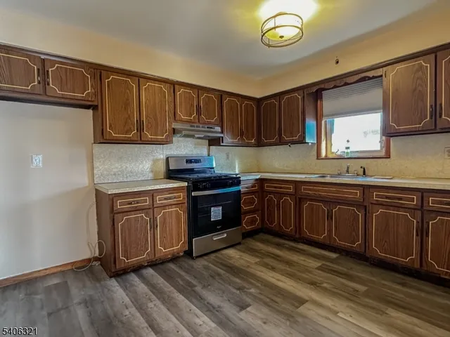 a kitchen with stainless steel appliances granite countertop a stove a sink dishwasher and a microwave with wooden cabinets