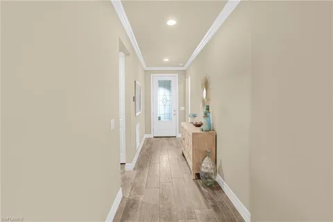 a view of a hallway with wooden floor and a bathroom