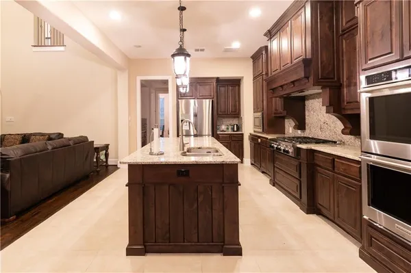 a kitchen with kitchen island granite countertop a sink stove and refrigerator