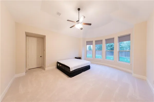an empty room with chandelier fan and windows