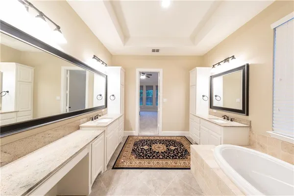 a bathroom with a tub a sink and a large mirror