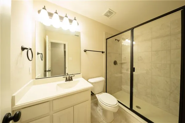 a bathroom with a shower sink vanity mirror and toilet