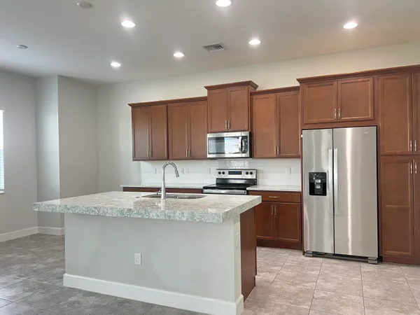 a kitchen with kitchen island granite countertop stainless steel appliances and refrigerator
