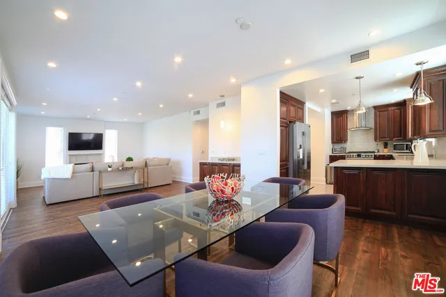 a living room with stainless steel appliances furniture and a kitchen view