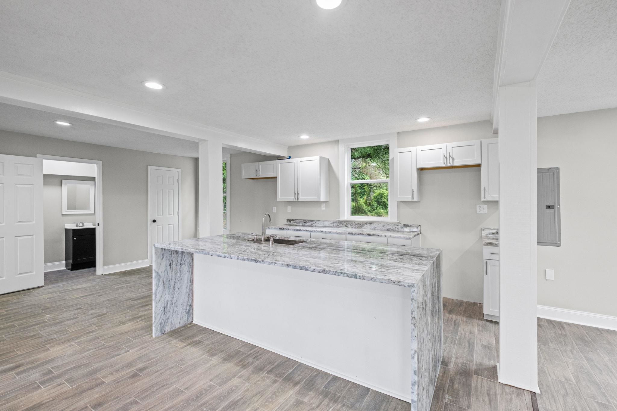 5843 Stewart Road Lakeland, TN 38002 - Photo 12 of 26 Kitchen featuring a waterfall island with stone countertop, stainless steel sink, and white cabinetry