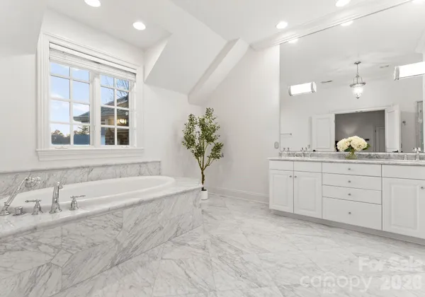 a spacious bathroom with a tub sink and mirror