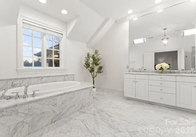 a spacious bathroom with a tub sink and mirror