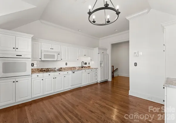 a large white kitchen with wooden floor