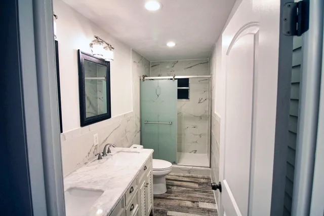 a bathroom with a granite countertop sink toilet and shower