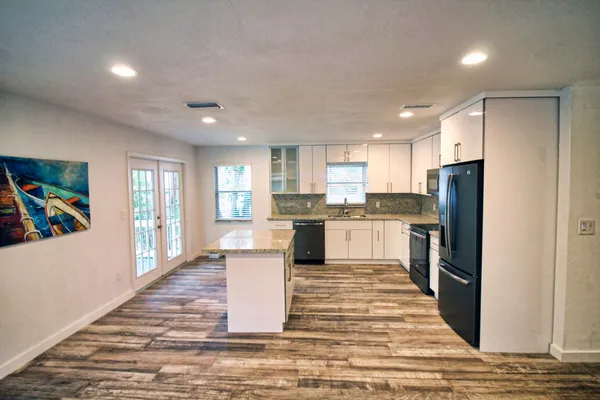 a kitchen with stainless steel appliances kitchen island granite countertop a refrigerator a stove top oven a sink and dishwasher