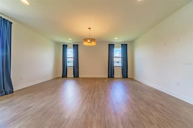 a view of an empty room with wooden floor and windows