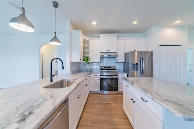 a view of a kitchen with granite countertop a large counter top a stove a sink cabinets and living room view