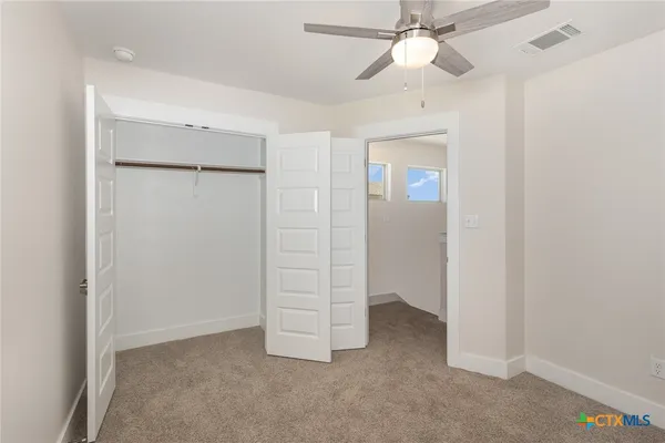 an empty room with closet and a chandelier fan