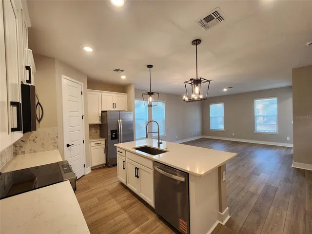 a kitchen that has a lot of cabinets in it and wooden floors