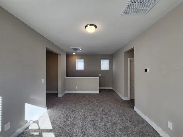 a view of an empty room with window and a kitchen