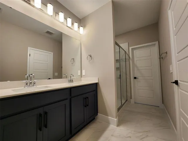 a bathroom with a double vanity sink mirror and shower