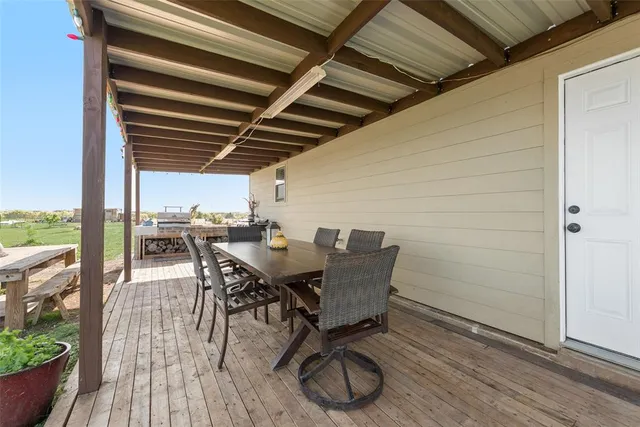 a view of a roof deck with table and chairs a barbeque with wooden floor and fence
