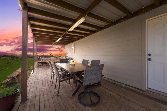 a patio with wooden floor a yard a table and chairs