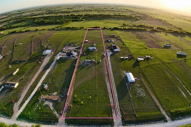 a view of a large garden with lawn chairs under an umbrella