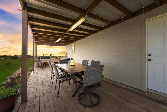 a view of a roof deck with table and chairs a barbeque with wooden floor and fence