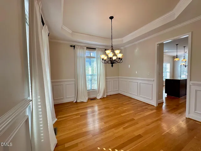 a view of a livingroom with a chandelier fan and wooden floor