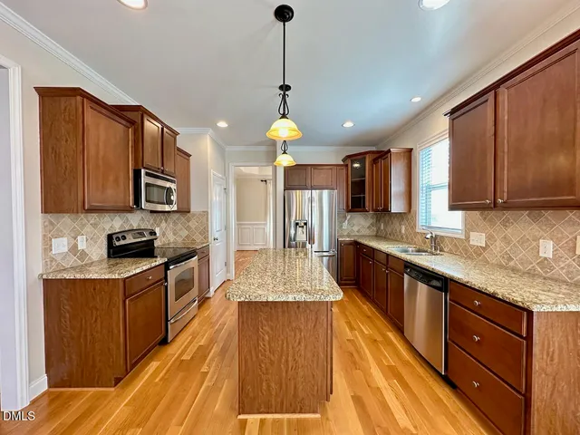 a large kitchen with granite countertop a large counter top space a sink stainless steel appliances and cabinets