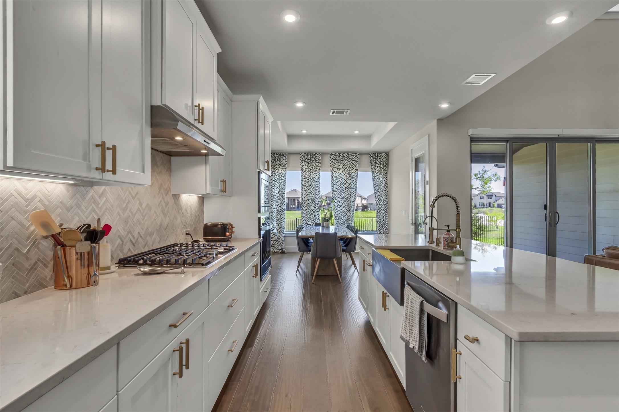 209 Azalea Spg Road Liberty Hill, TX 78642 - Photo 14 of 29 Kitchen featuring light cabinetry with gold-toned hardware, white countertops, and a herringbone backsplash