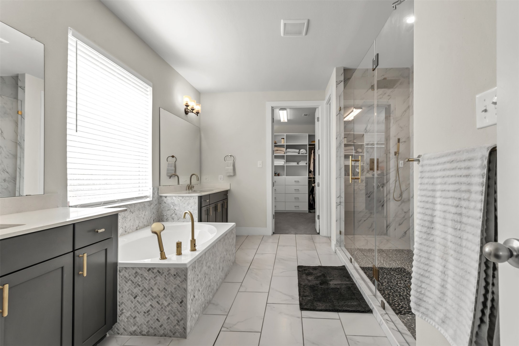 209 Azalea Spg Road Liberty Hill, TX 78642 - Photo 18 of 29 Spacious bathroom featuring a freestanding tub with gold-tone fixtures, a glass-enclosed shower with pebble-tile flooring, and dual vanities with quartz countertops