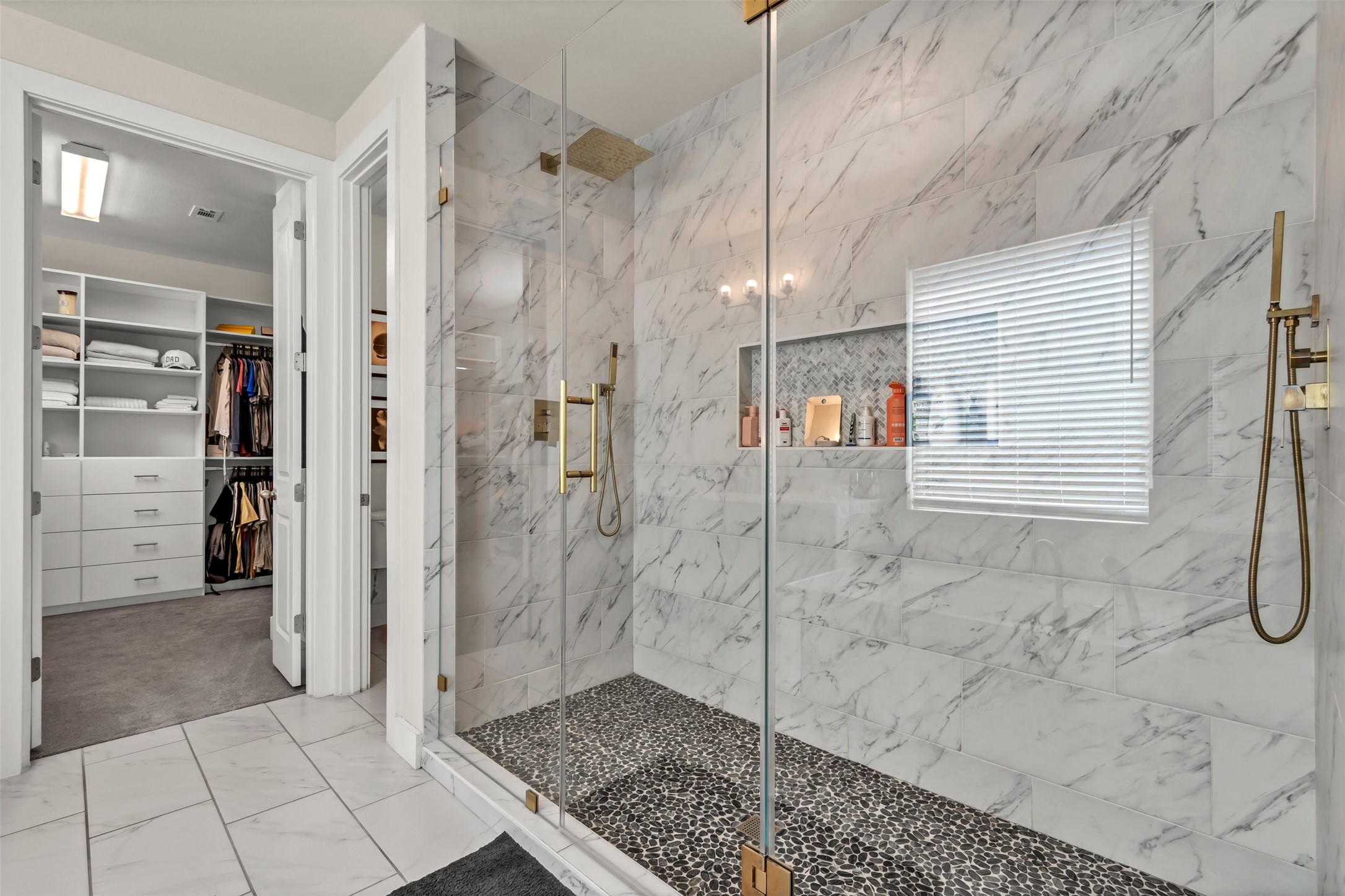 209 Azalea Spg Road Liberty Hill, TX 78642 - Photo 19 of 29 Shower enclosure featuring large format white tiled walls, a pebbled floor, and gold-toned fixtures