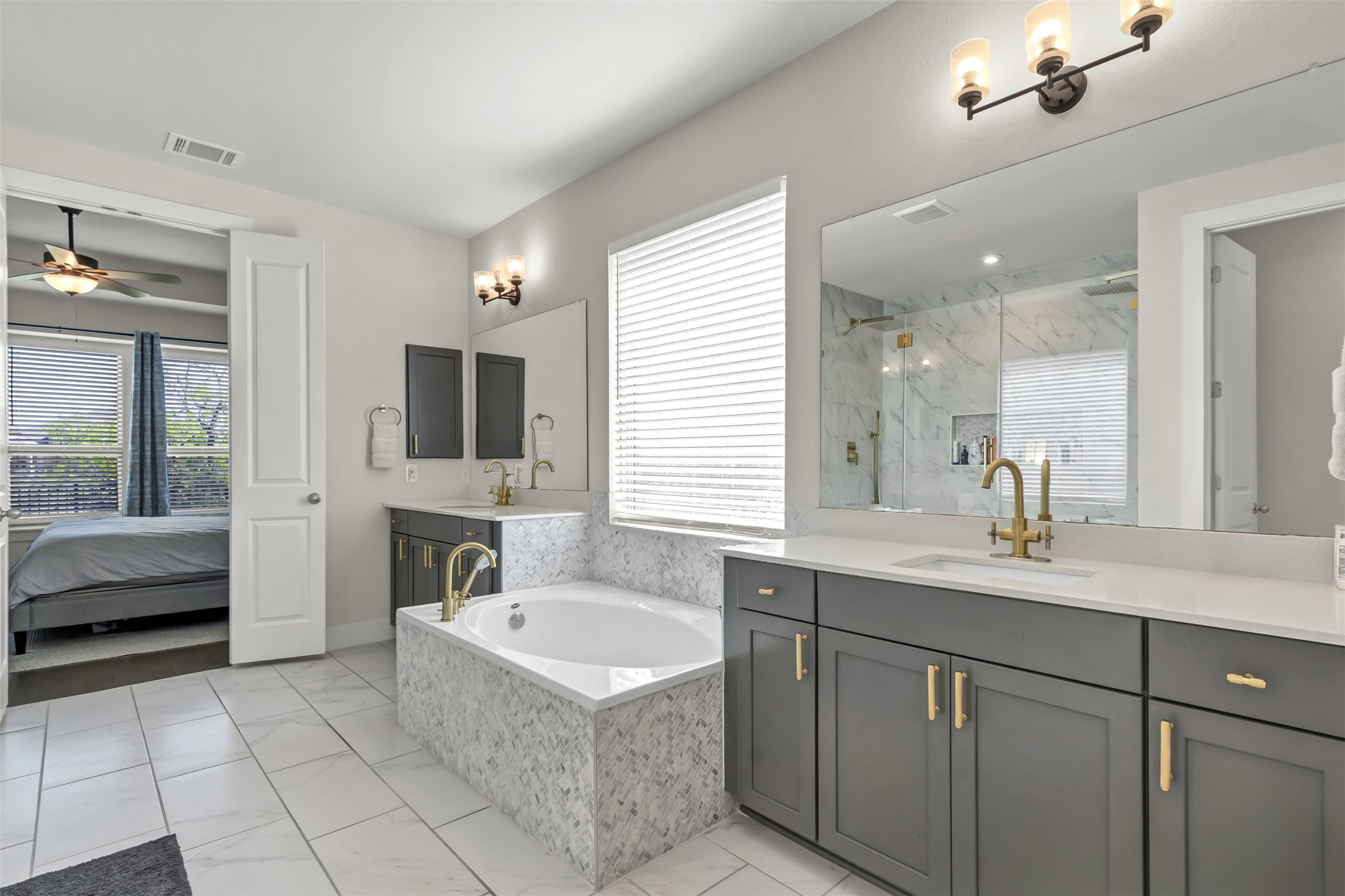 209 Azalea Spg Road Liberty Hill, TX 78642 - Photo 20 of 29 Spacious bathroom featuring a built-in soaking tub with a tiled surround, dual vanity with white countertops, a large walk-in shower with glass enclosure, and white tile flooring
