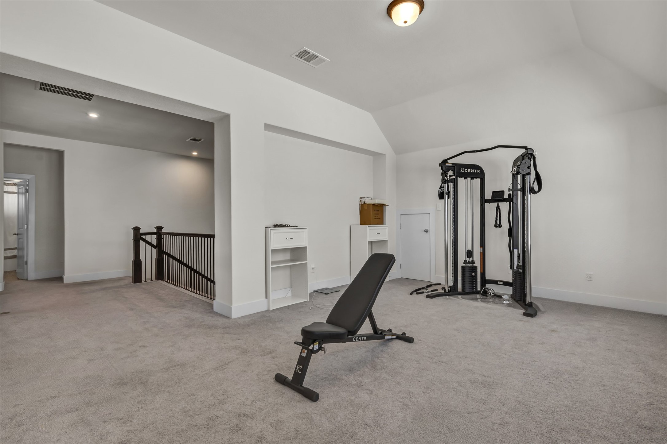 209 Azalea Spg Road Liberty Hill, TX 78642 - Photo 22 of 29 Spacious carpeted room featuring vaulted ceilings, recessed lighting, a built-in shelving unit, and a black wrought iron railing along the staircase opening