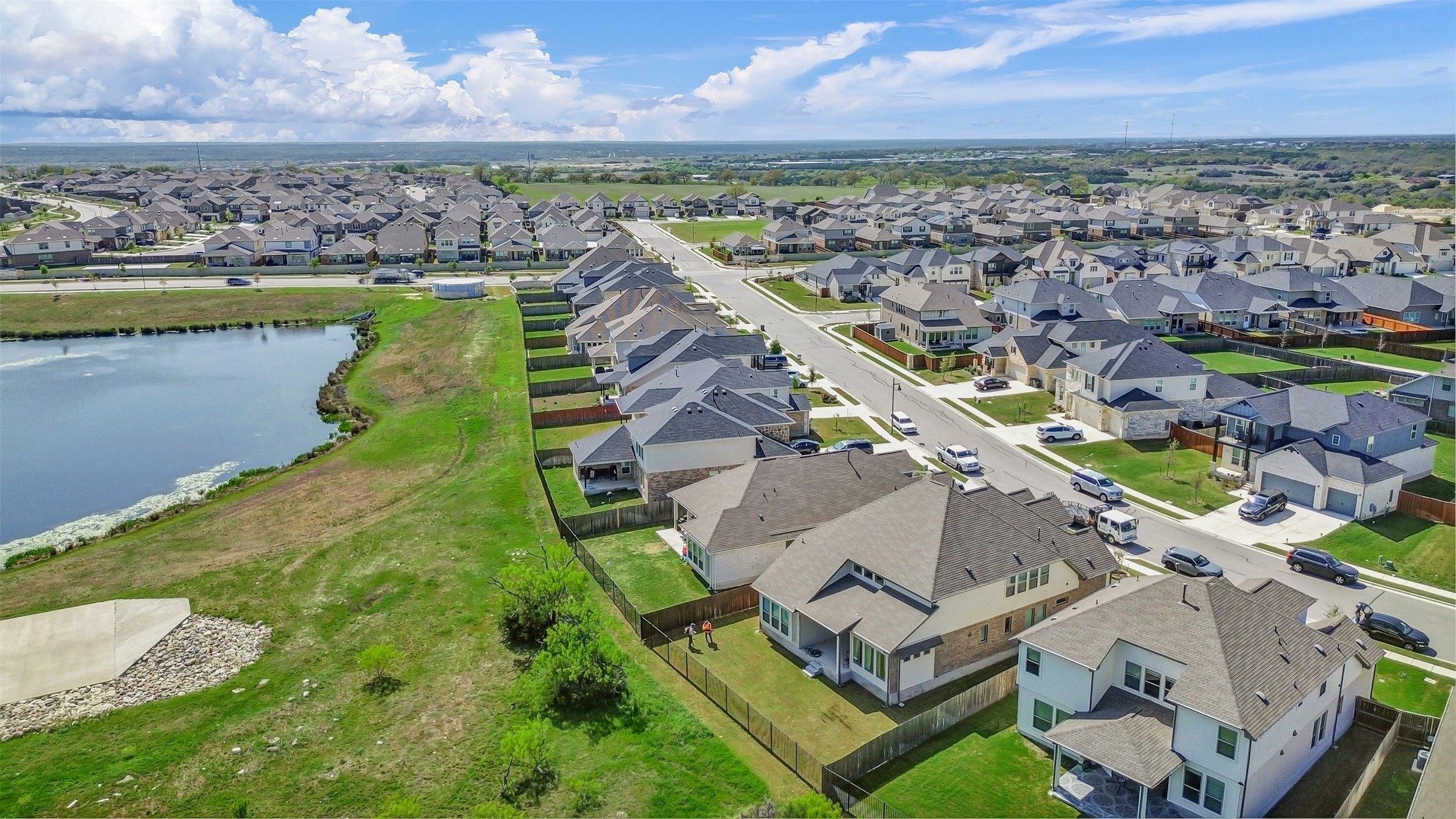 209 Azalea Spg Road Liberty Hill, TX 78642 - Photo 28 of 29 Residential neighborhood with diverse architectural styles, featuring a paved road, individual property fencing, and a nearby body of water