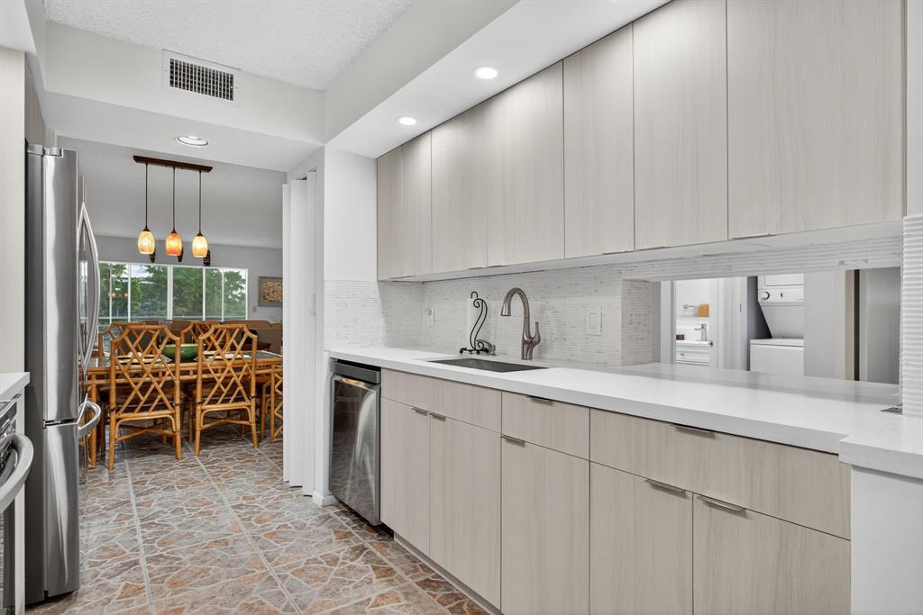 1801 Eleuthera Point, Unit D3 Coconut Creek, FL 33066 - Photo 10 of 80 a kitchen with kitchen island granite countertop a sink and white cabinets