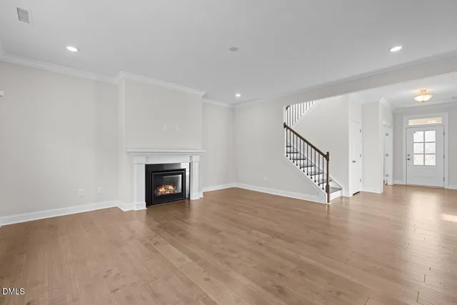 an empty room with wooden floor fireplace and windows