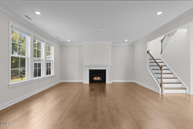 an empty room with wooden floor fireplace and windows