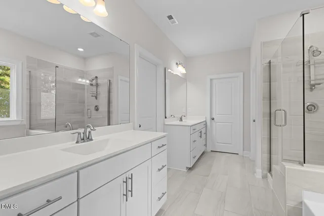 a bathroom with double vanity sinks a mirror a vanity and a shower