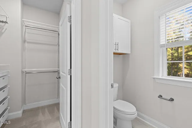 a bathroom with a granite countertop toilet a sink and a window