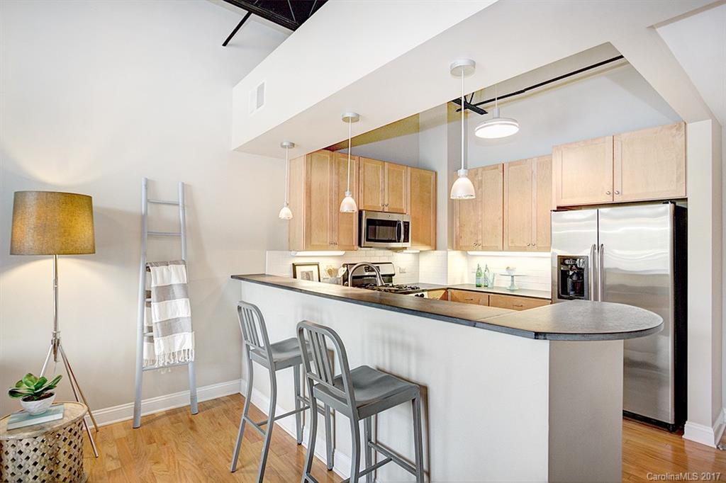 3920 Sharon Road, Unit 206 Charlotte, NC 28211 - Photo 2 of 24 a kitchen with stainless steel appliances granite countertop a refrigerator a sink a stove a dining table and chairs with wooden floor