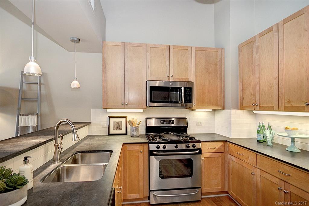 3920 Sharon Road, Unit 206 Charlotte, NC 28211 - Photo 4 of 24 a kitchen with stainless steel appliances granite countertop a sink a stove and a microwave with wooden floor
