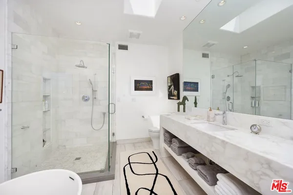 a spacious bathroom with a double vanity sink toilet mirror and shower