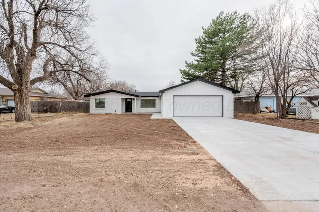 a front view of house with garage and trees