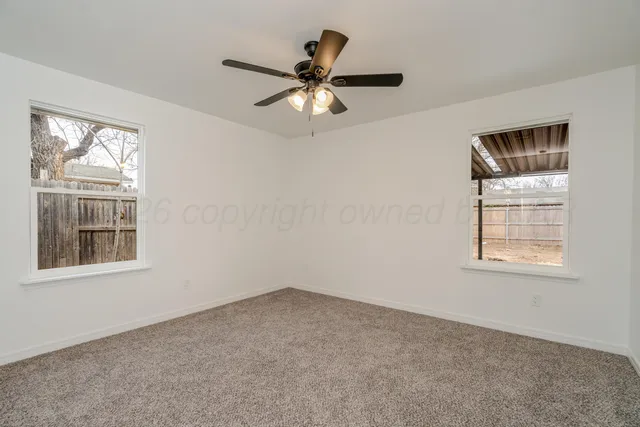 an empty room with windows and fan