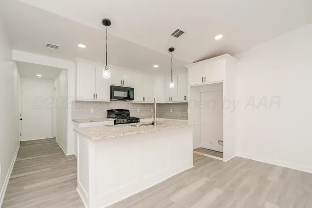 a kitchen with kitchen island a sink stainless steel appliances and white cabinets