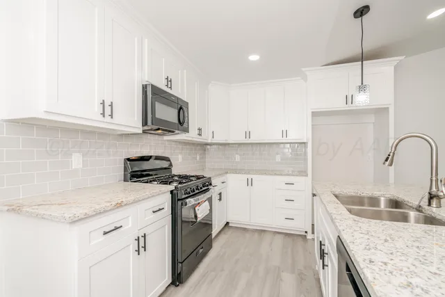 a kitchen with granite countertop a sink a stove and cabinets