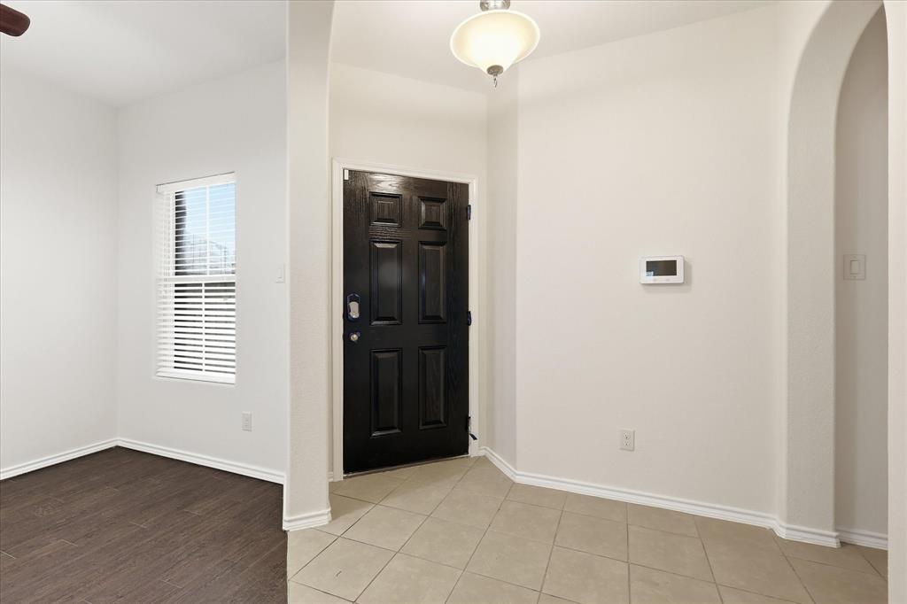 720 Rio Bravo Drive Fort Worth, TX 76052 - Photo 5 of 38 Entry foyer featuring a paneled door, tile flooring, and arched doorway