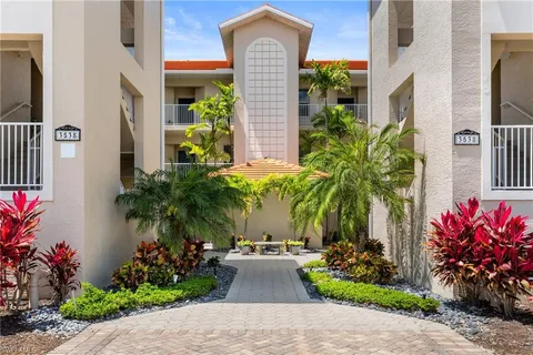 a front view of a house with lots of flower plants and wooden fence